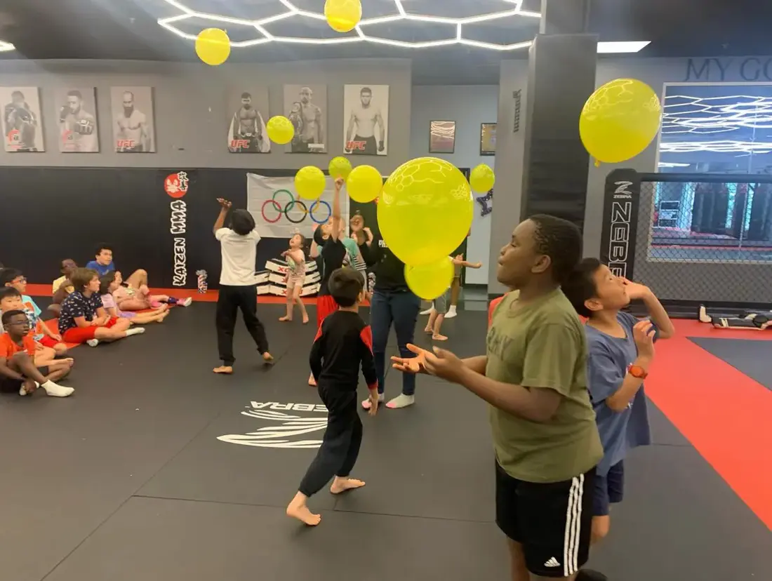 Children playing a balloon game together in a large indoor space