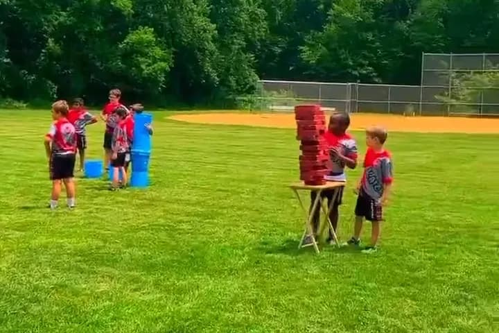 Children playing a giant jenga game on a grass field on a summer day