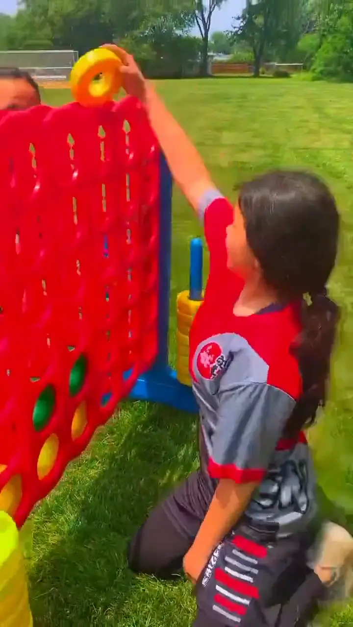 Children playing giant Connect Four and giant Jenga on a grass field